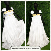 White evening gown with gold accents on a mannequin against a green grass background
